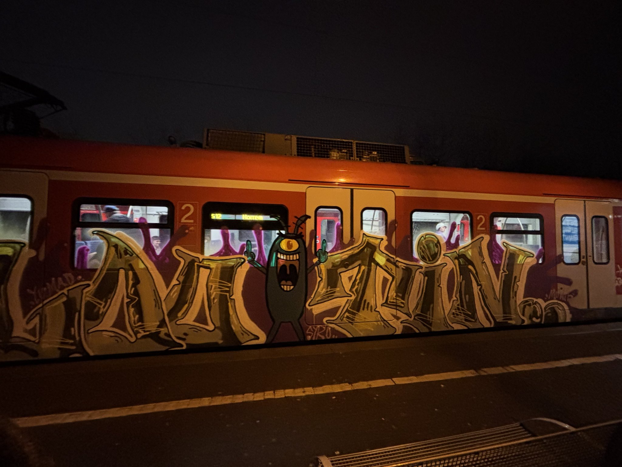 some grafitti on an s-bahn train, with the character plankton from spongebob raising a double middle finger, text surrounding is indecipherable to me