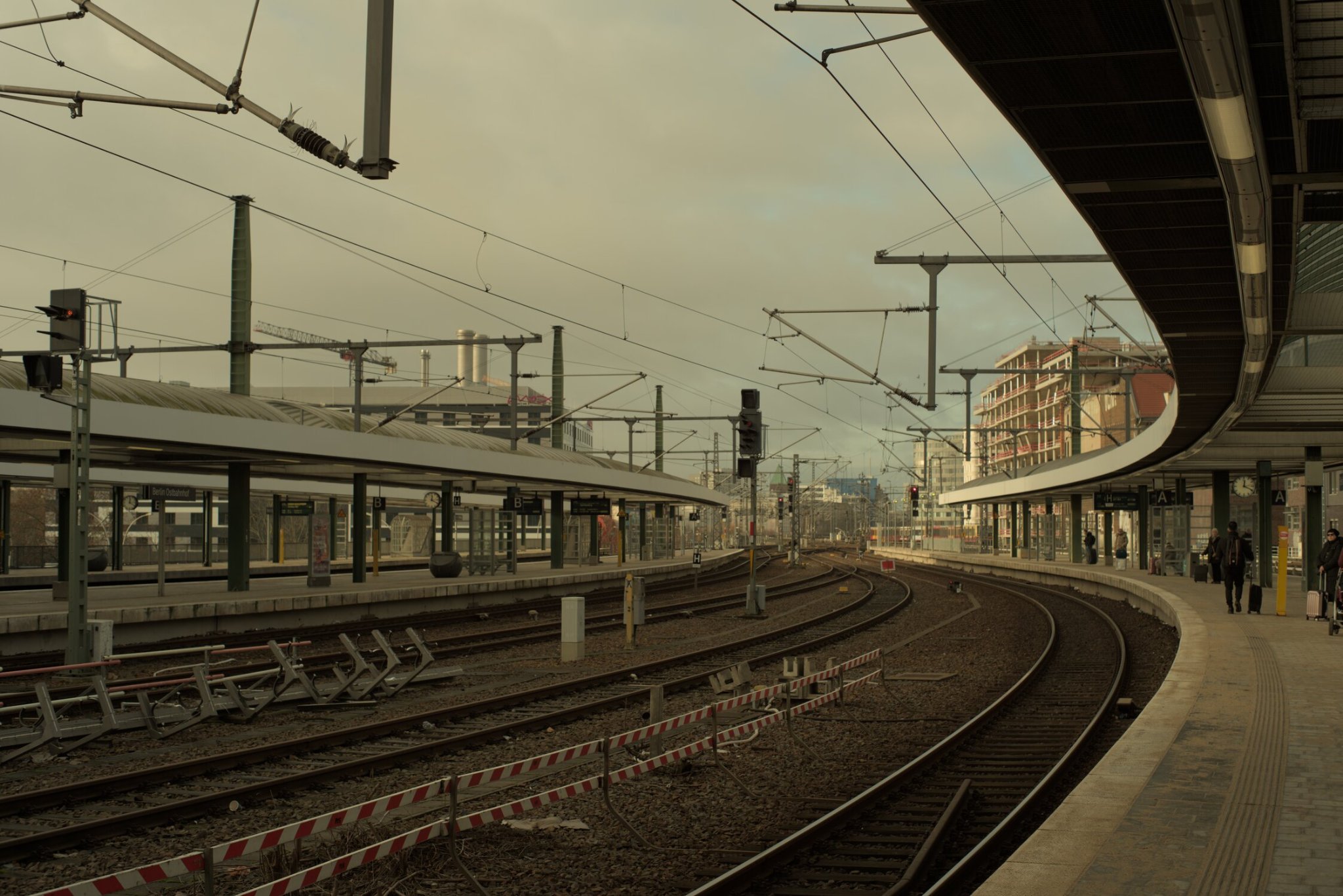 four adajacent, empty rails wait, yearning to be filled by trains soon to come, passengers waiting upon their platforms