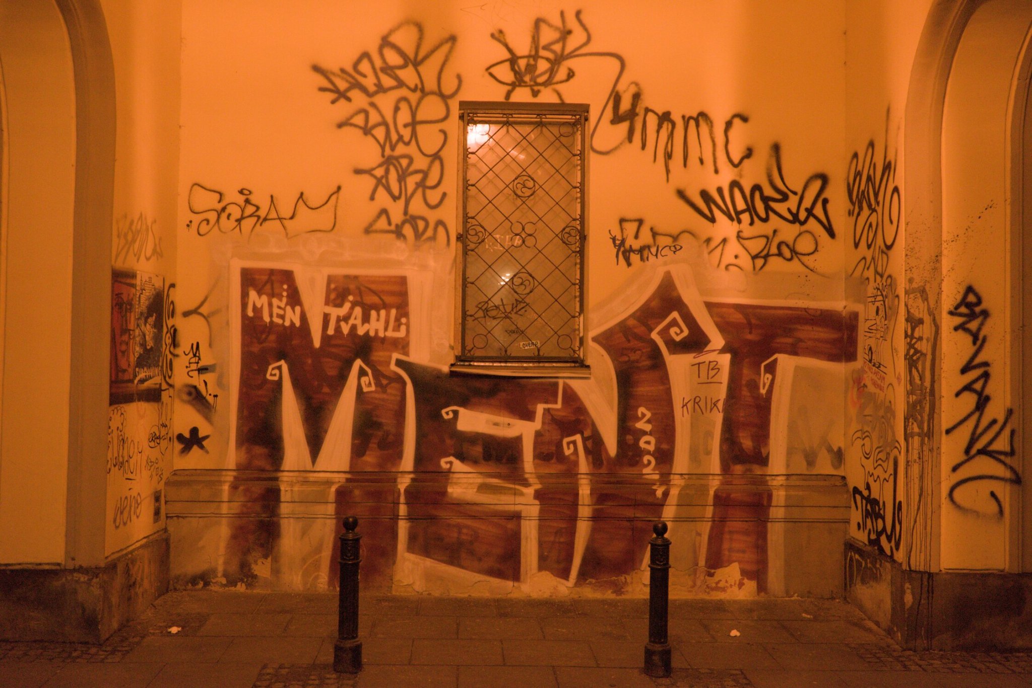 a wall of grafitti, situated behind two bollards, blocking the window beyond... this one also got the double whammy warm glow from lens and lighting combo