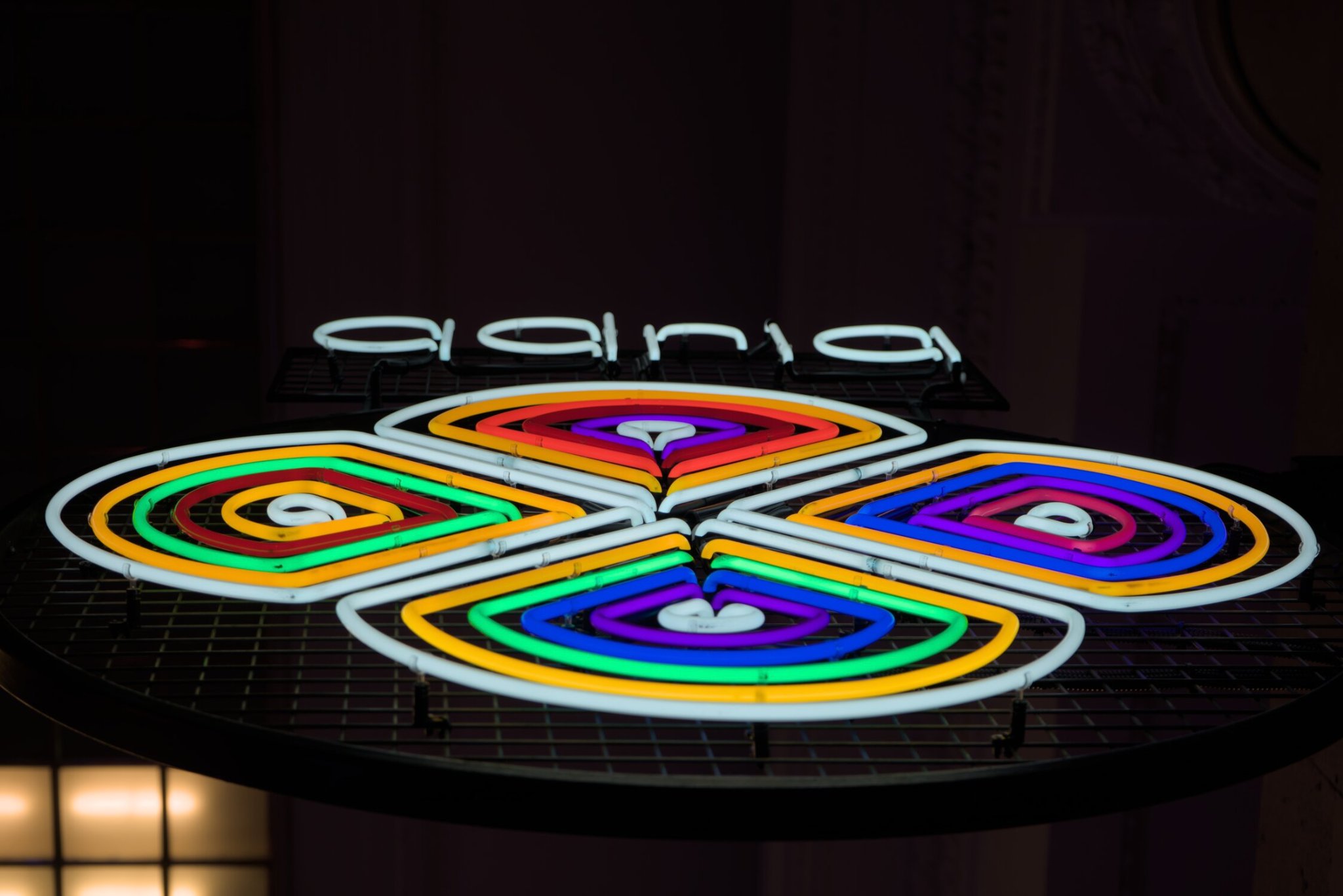 a sign shaped like a flower, as seen from below.... the colors are a super saturated and intense rainbow