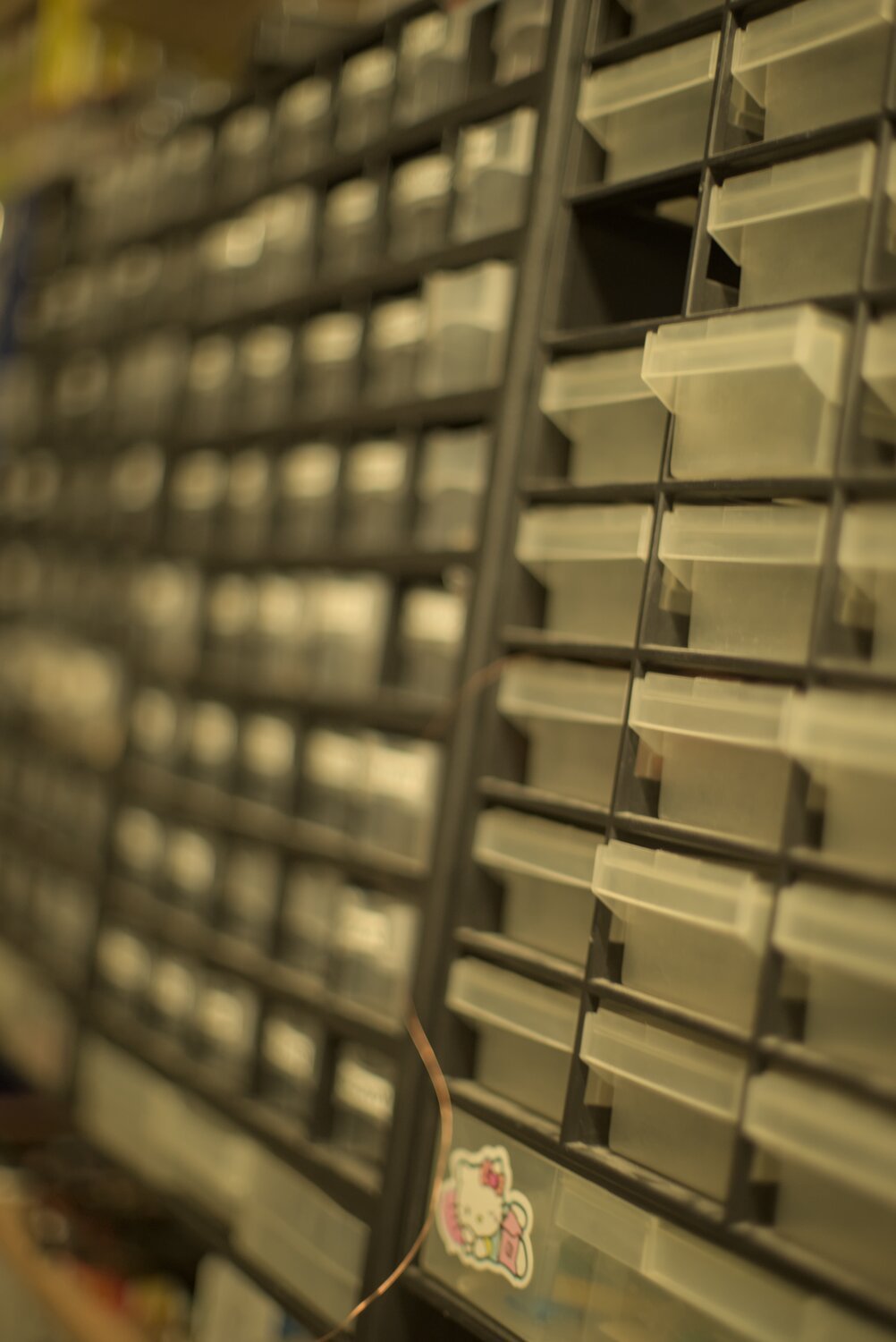 a wall of organization boxes with a super narrow focus band, a copper wire sticking out of one, and a 'hello kitty' sticker adorning another