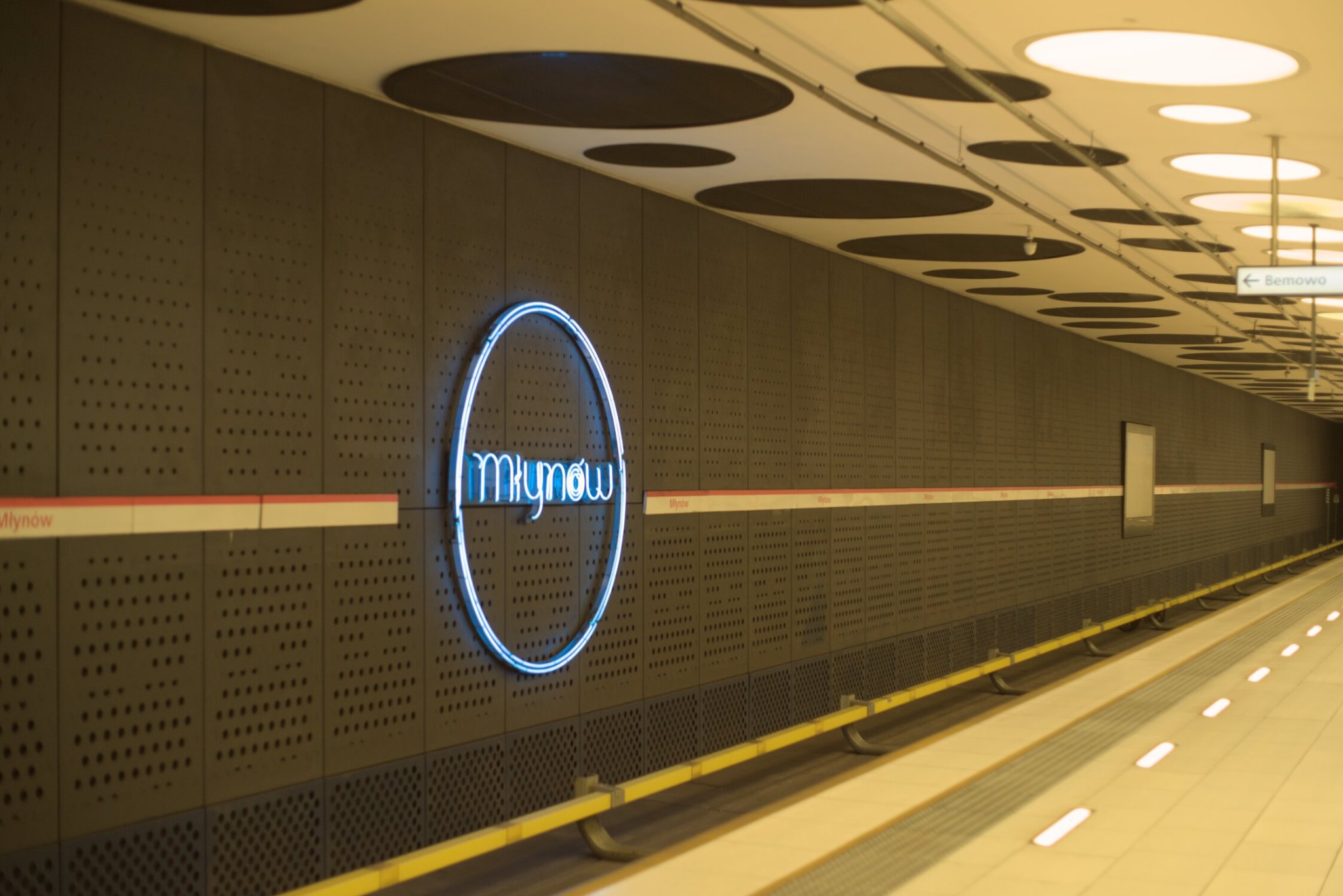 a metro stop, adorned with neon, the location being młynow, the neon being a simple circle with the station's name within