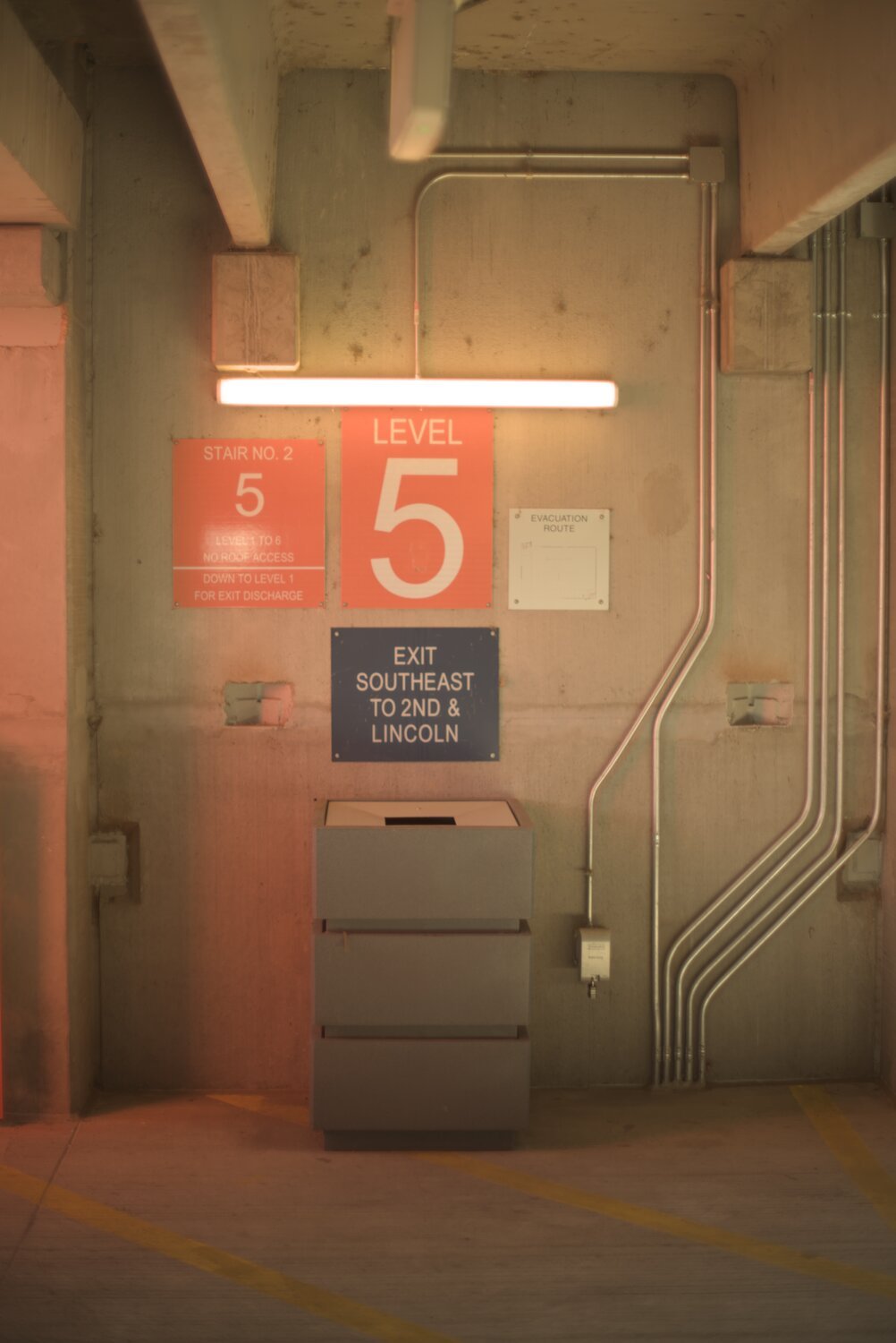 some stairway level signs, 'level 5; exit southeast to 2nd and lincoln'