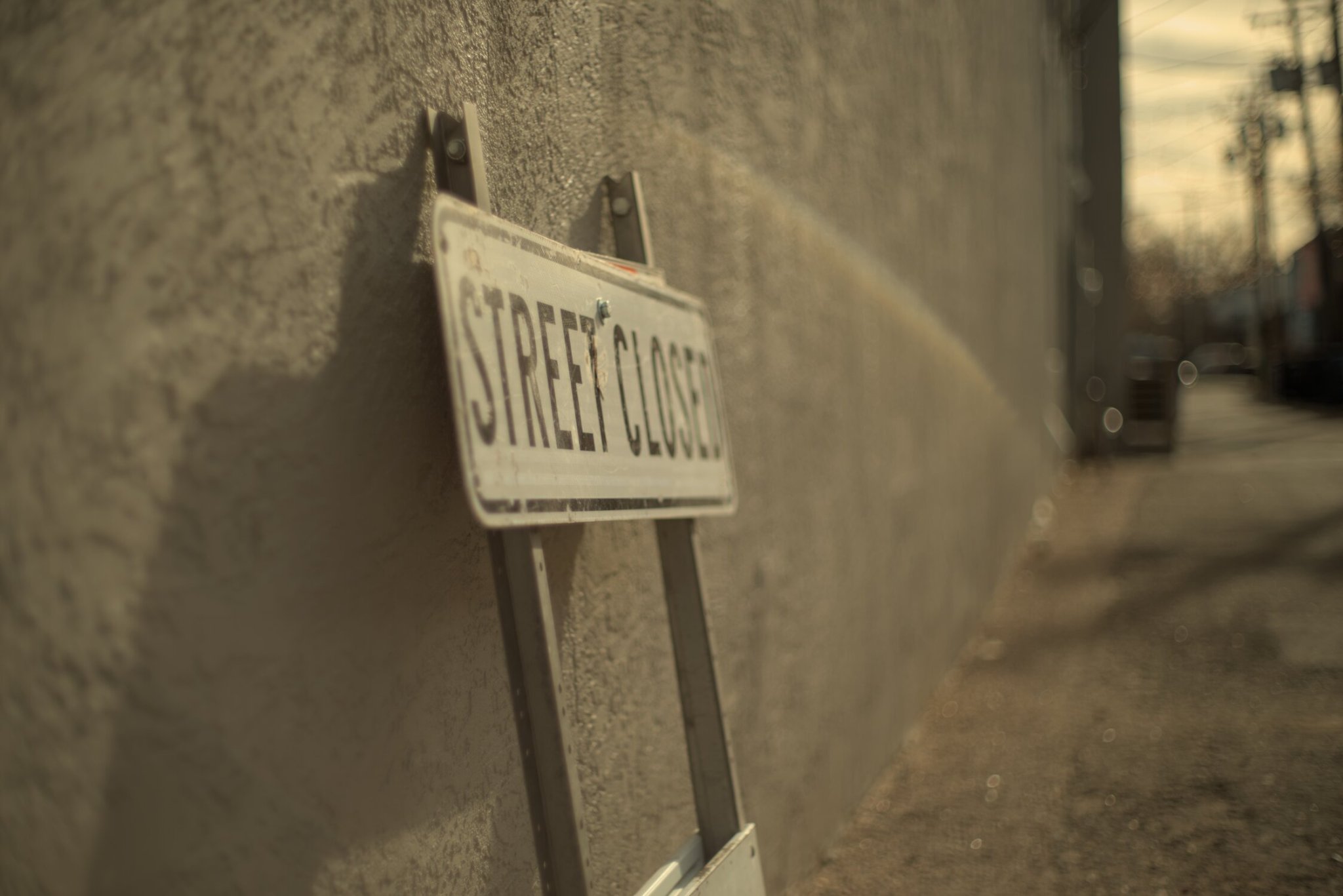 a 'street closed' sign leaned against a wall, lens flares and bokeh abound