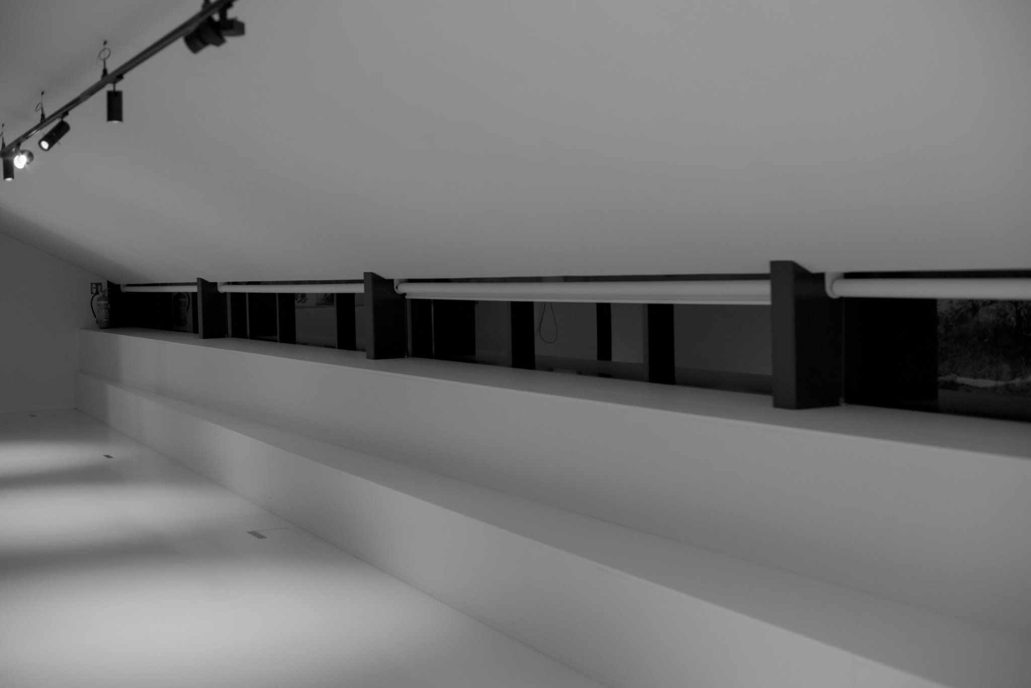 a monochrome platform with windows behind, to the left of frame is a fire extinguisher