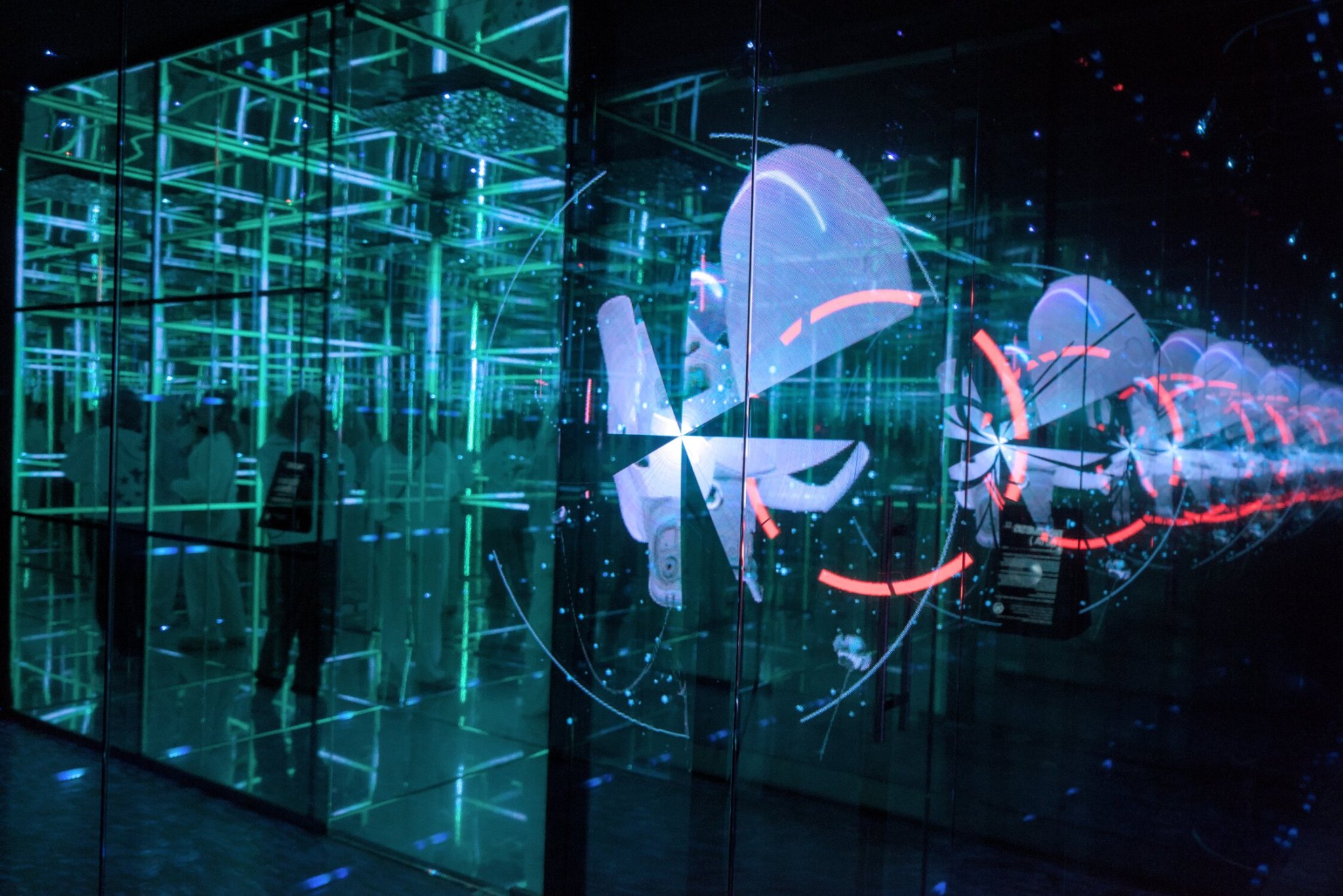 a view into a mirroed led box on the left of the frame, an led fan caught in shutter speed on the right, a patron can be seen enjoying the box
