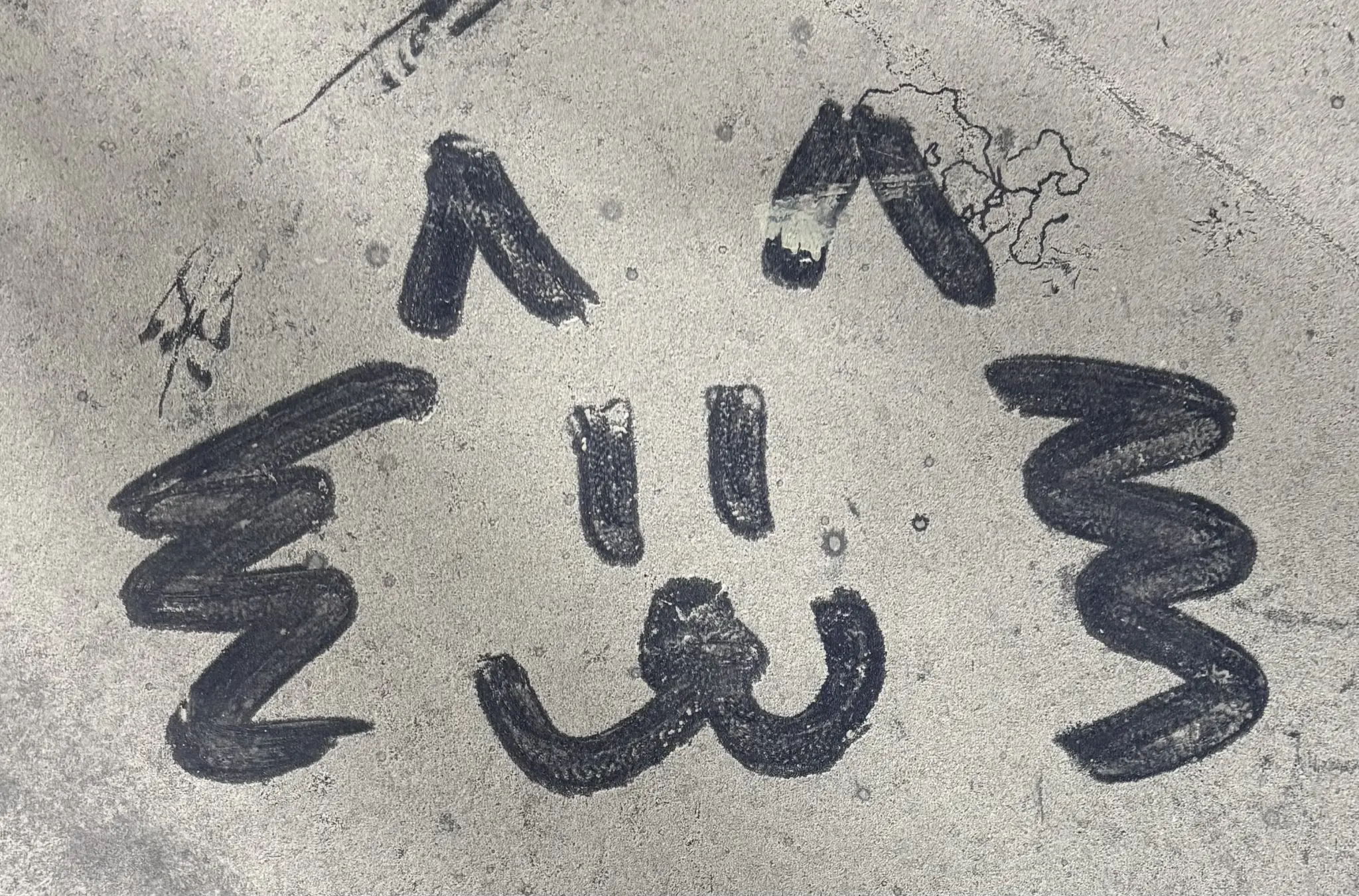 a cartoonish cat face drawn in a thick layer of dust