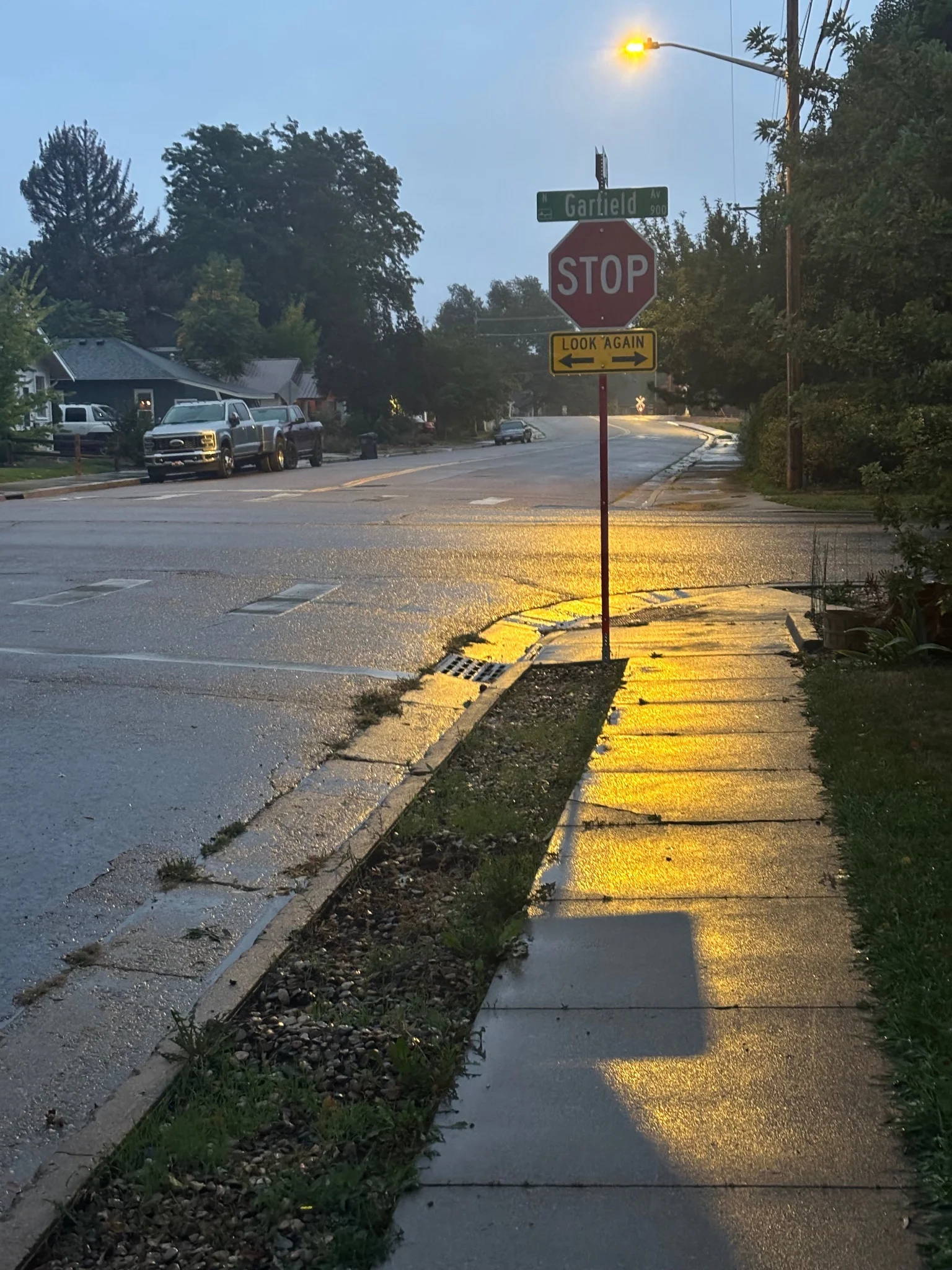 a stop sign, looking ominously upon the viewer, silhouetted by the lamp post beyond, the shadow stretching out, almost as though to touch you