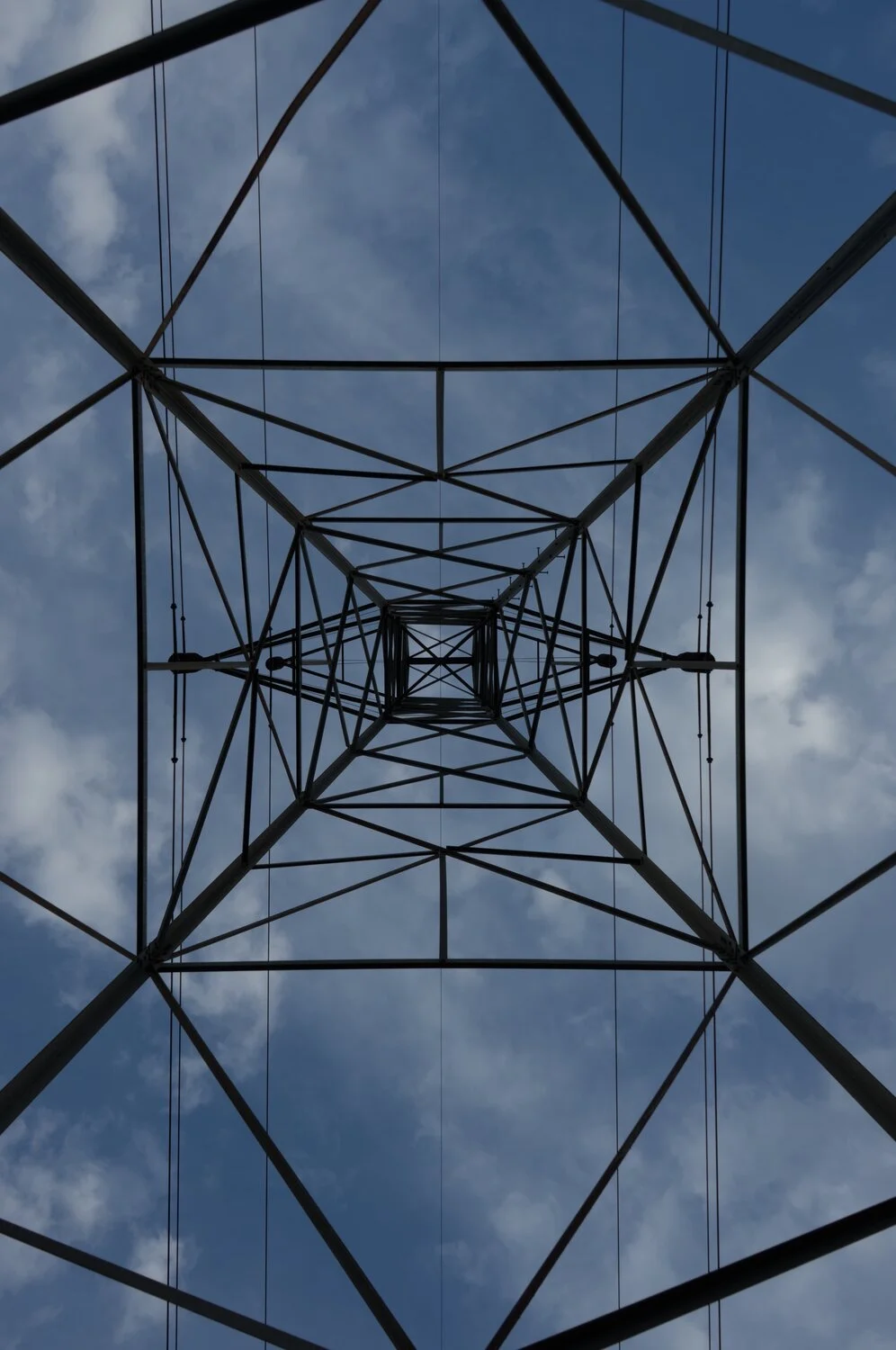 a high voltage power transmission tower, as viewed from the bottom, looking up into the center of it