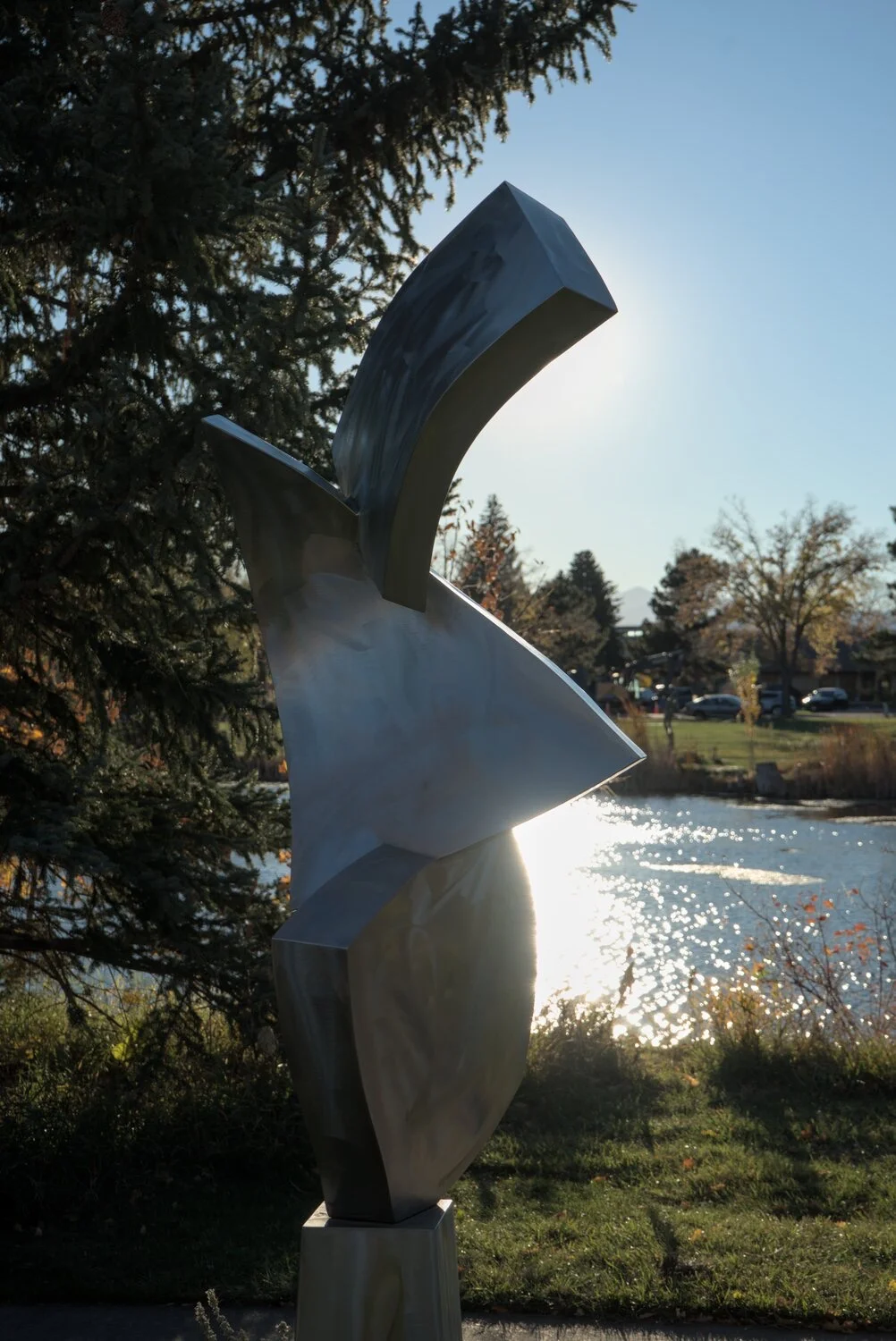 a stainless steel statue of shapes, with the sun behind it, making the background very bright
