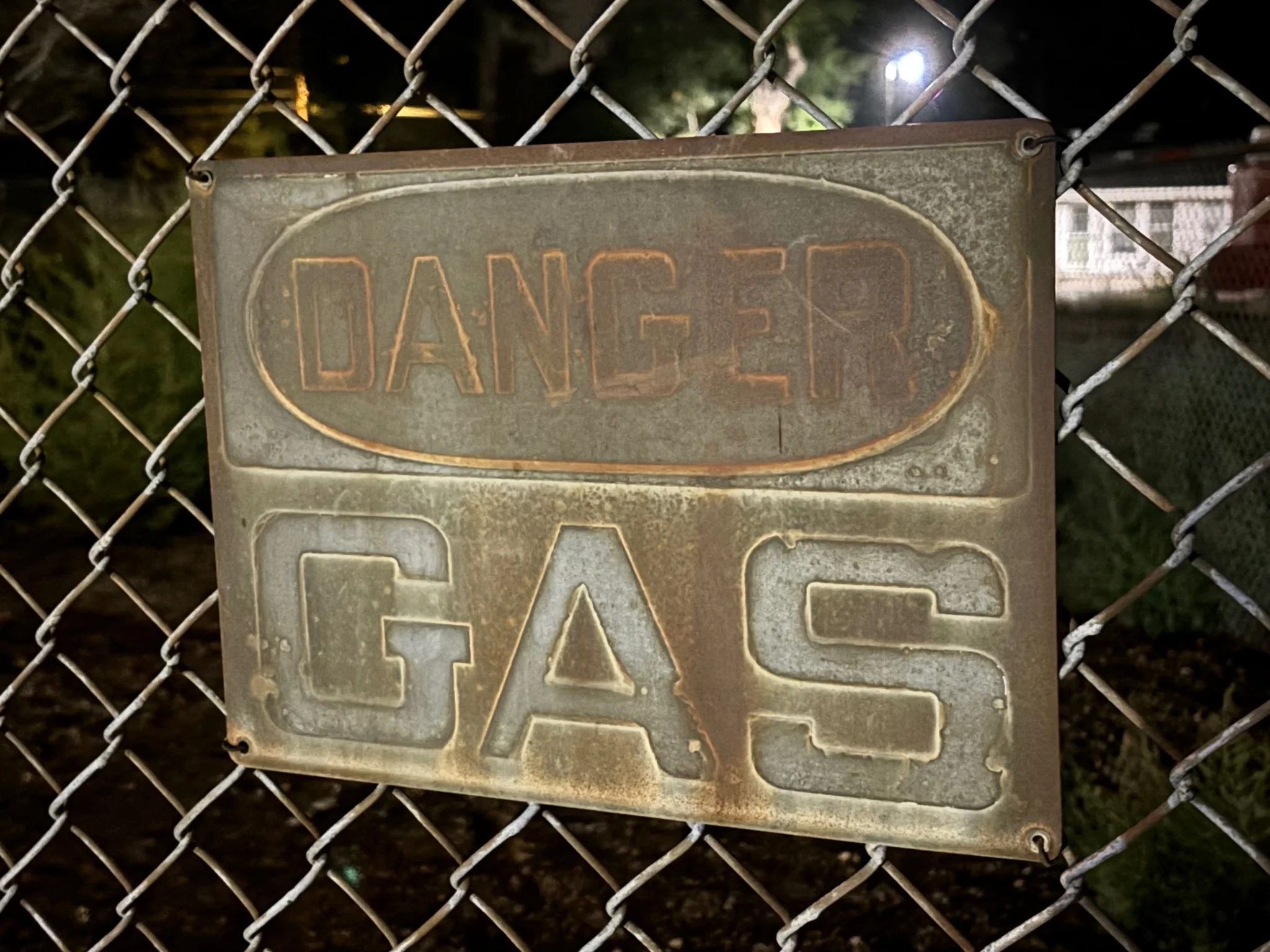 a very weathered sign that says 'Danger Gas'