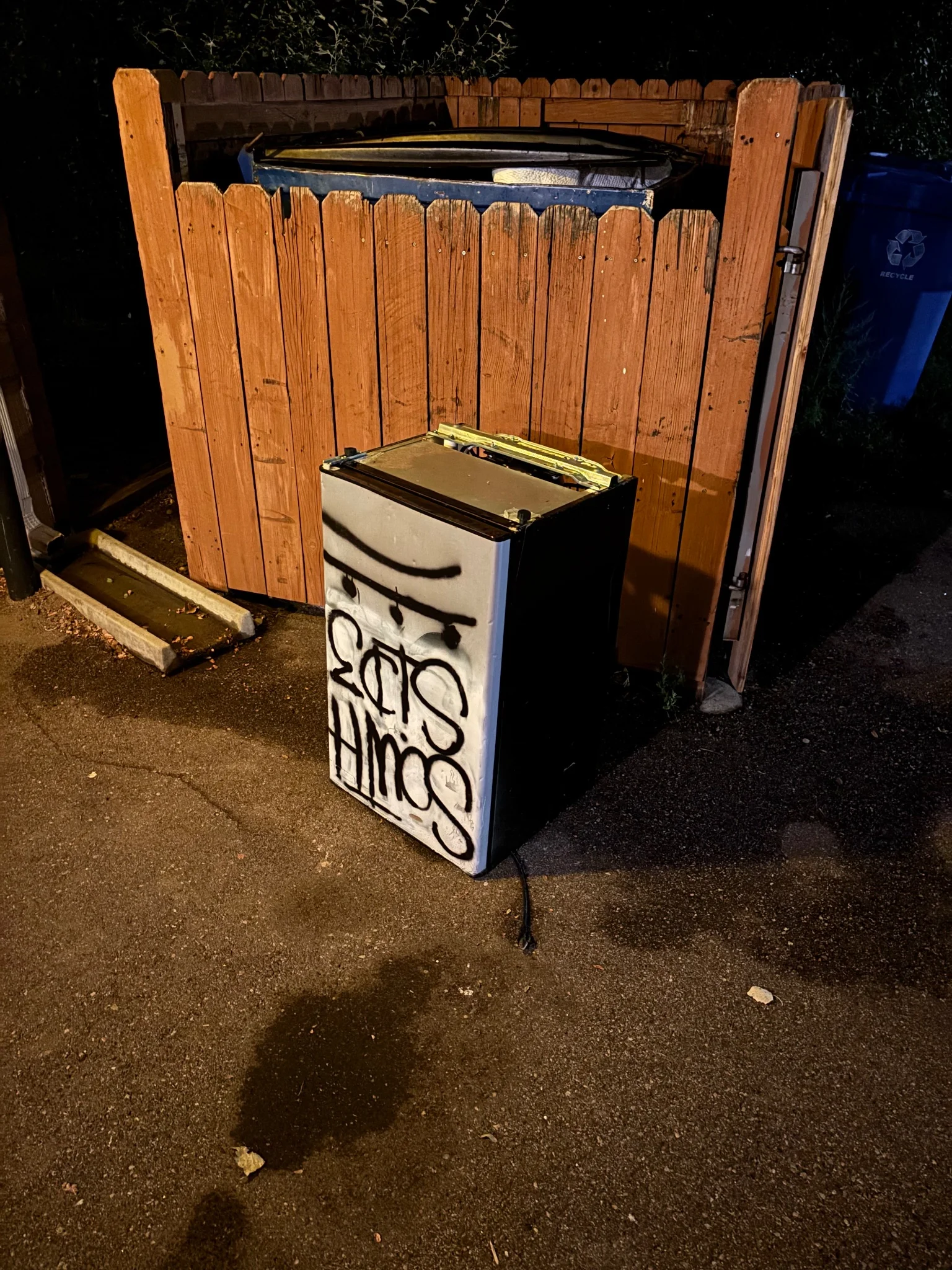 an upside down mini fridge, in front of a fenced off dumpster
it has 'south side' painted on to it in graffiti style, which is a bit strange as there isn't any other graffiti in the area...