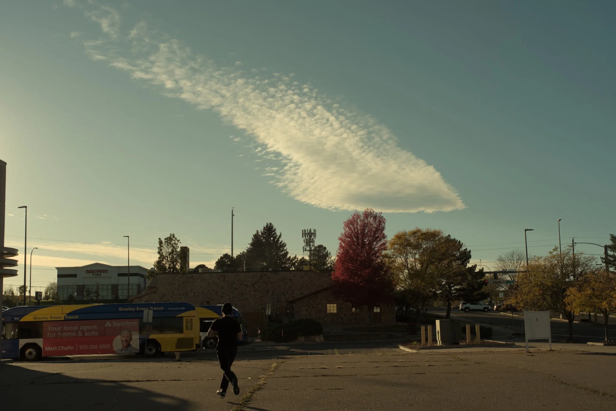 the sky with a smeary cloud, in the foreground is a person running for the bus, captured such that both feet are in the air