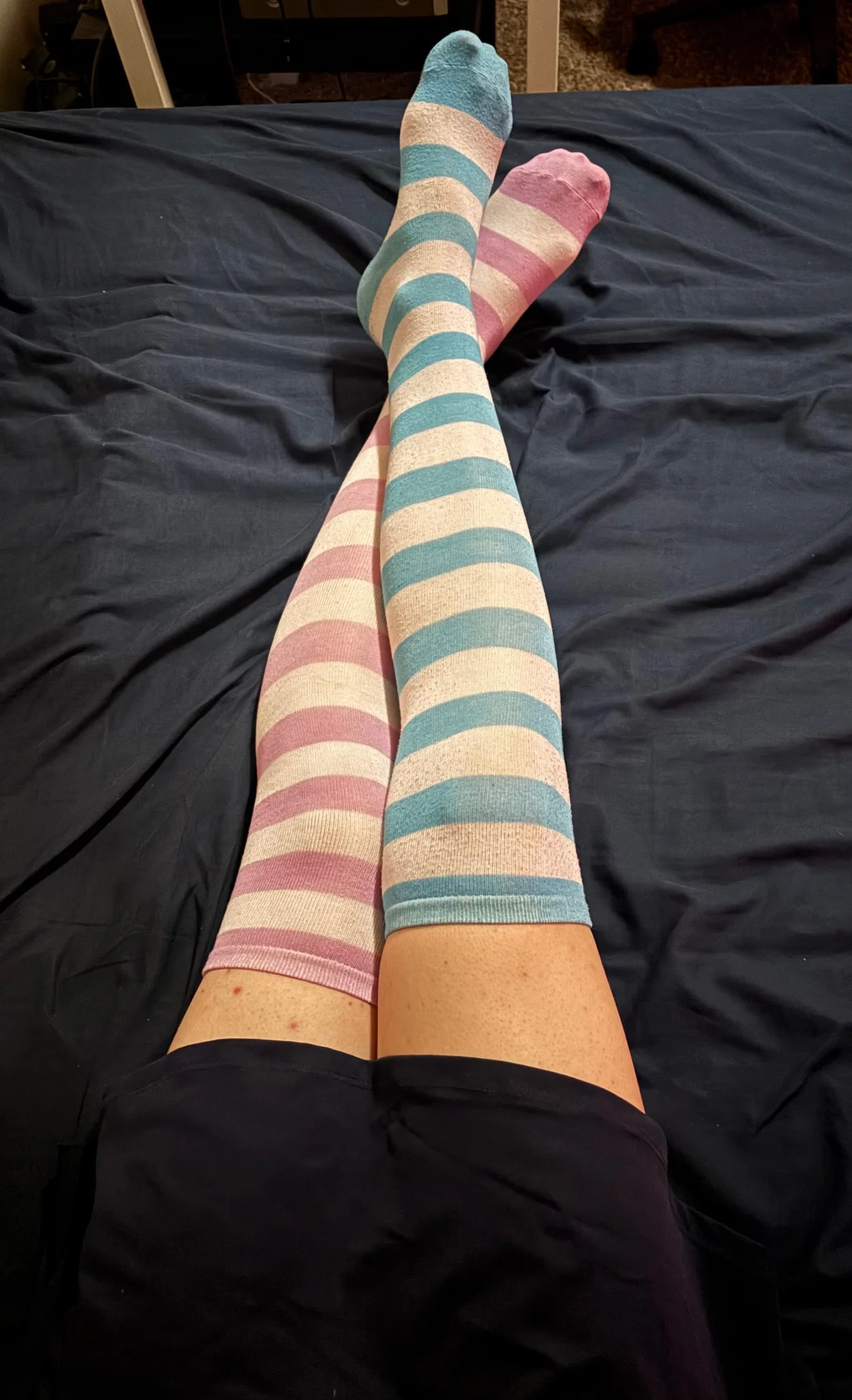 my legs! i'm lying in bed, wearing a skirt and knee high socks, white with blue stripes on the right and white with lavender stripes on the left, with my right leg crossed over the left
a very clear skirt to sock gap can be seen