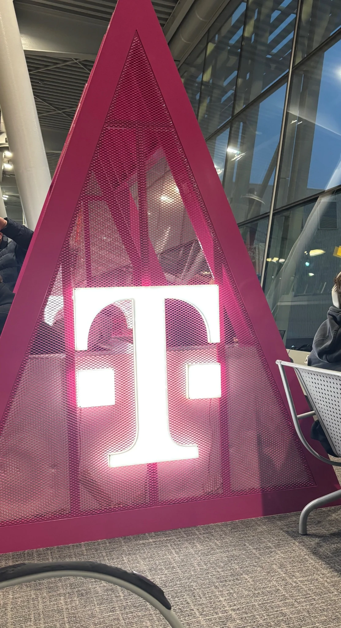 a pink metal mesh triangle, with an illuminated t-mobile logo upon the side facing the viewer, not seen are the multitude of outlets within
