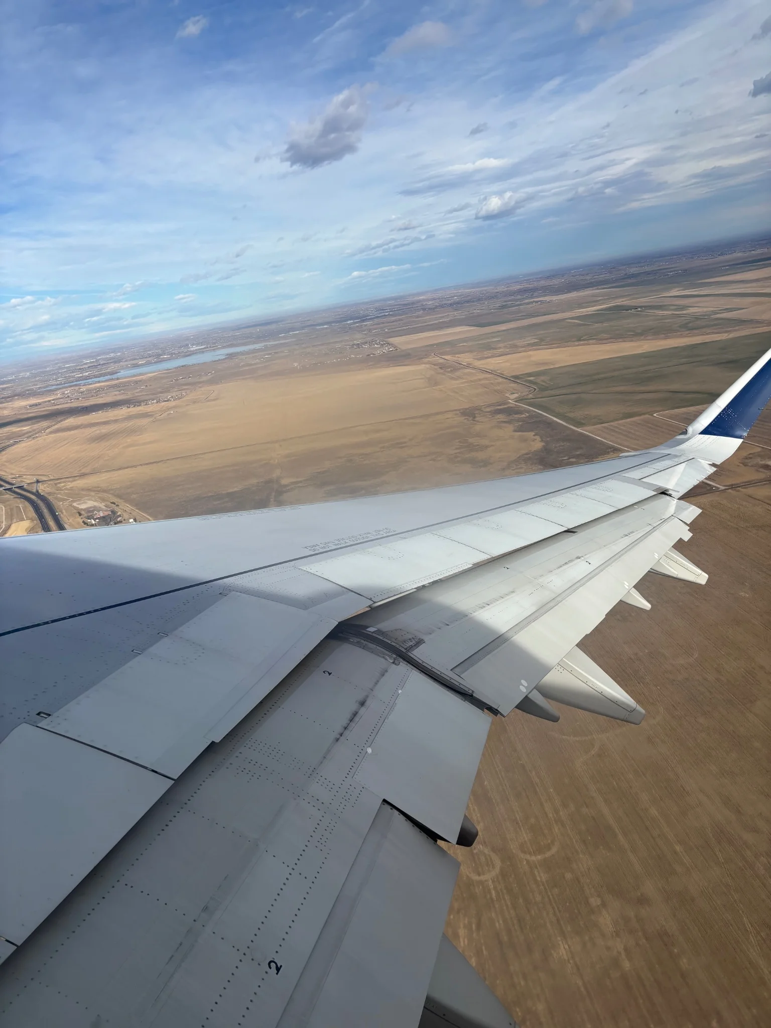 looking out over the wing of an ascending A321, we see the valleys of colorado and the horizon beyond