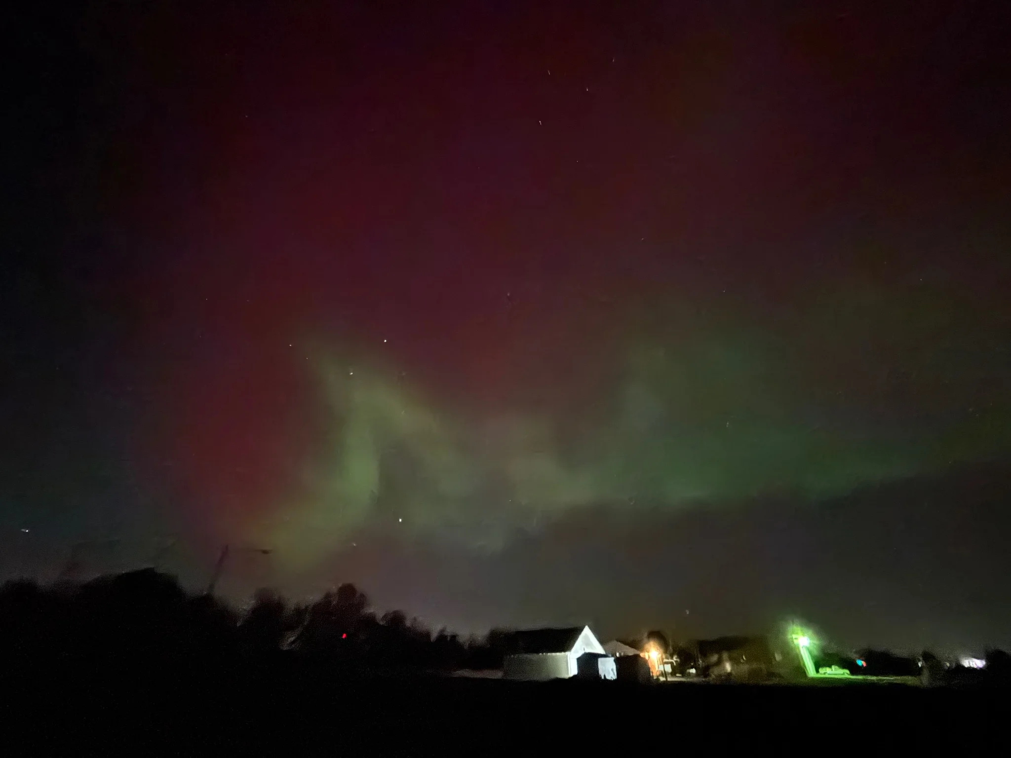 aurora, looking very red and green
a building is visible in the foreground 