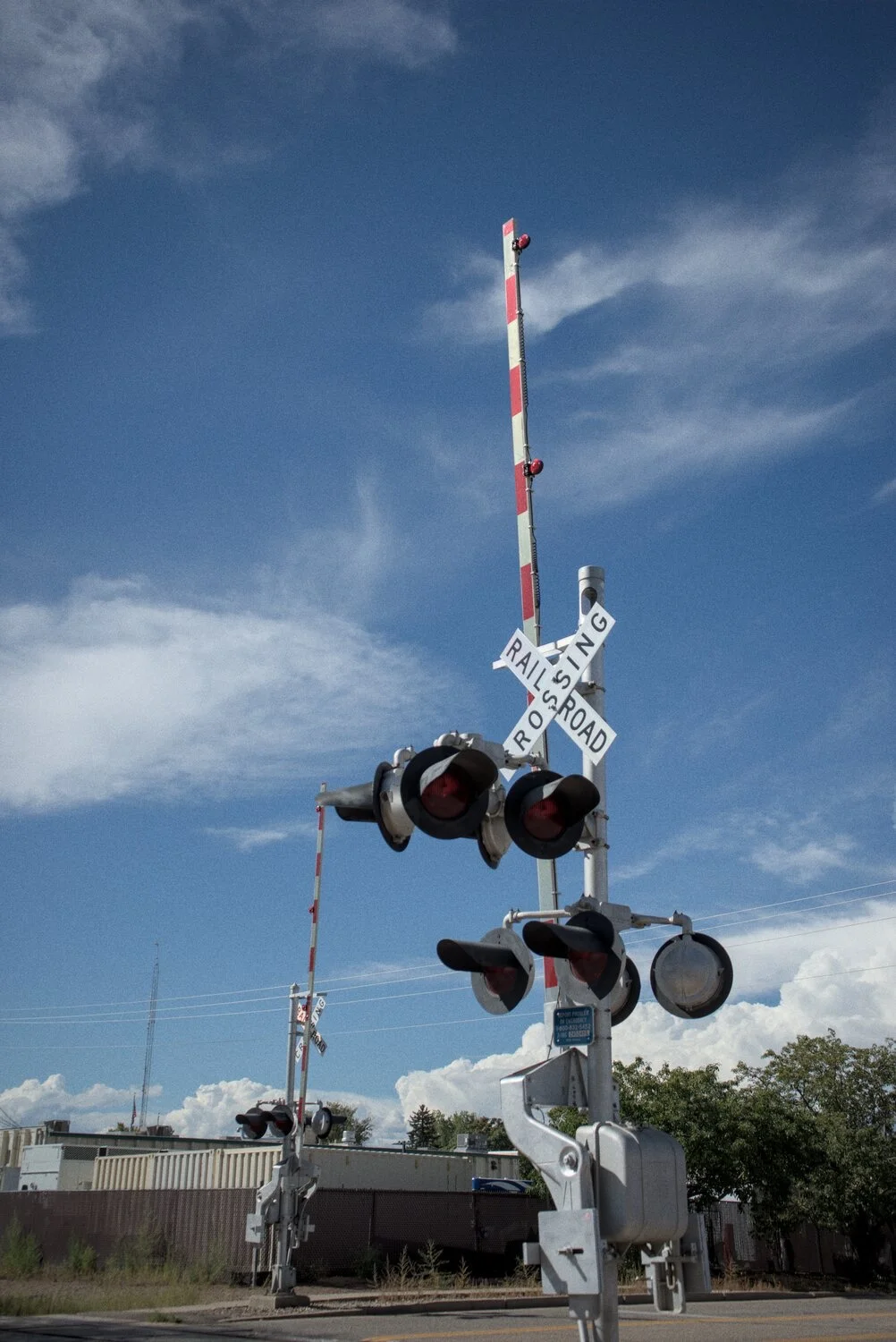 railroad crossing light, the bar is raised
the sky is lightly cloudy