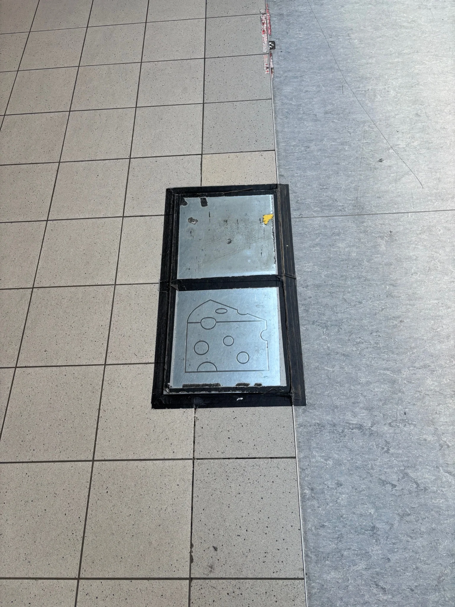 a metal floor panel with a cheese icon engraved on it