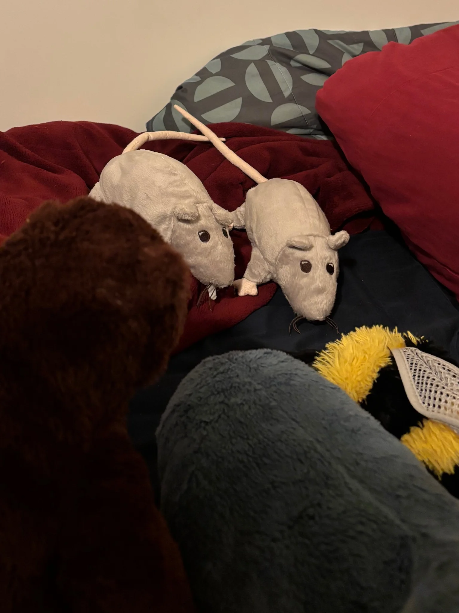 a bee, shark, and bear plush observe two rat plushies, almost as though they're in a meeting