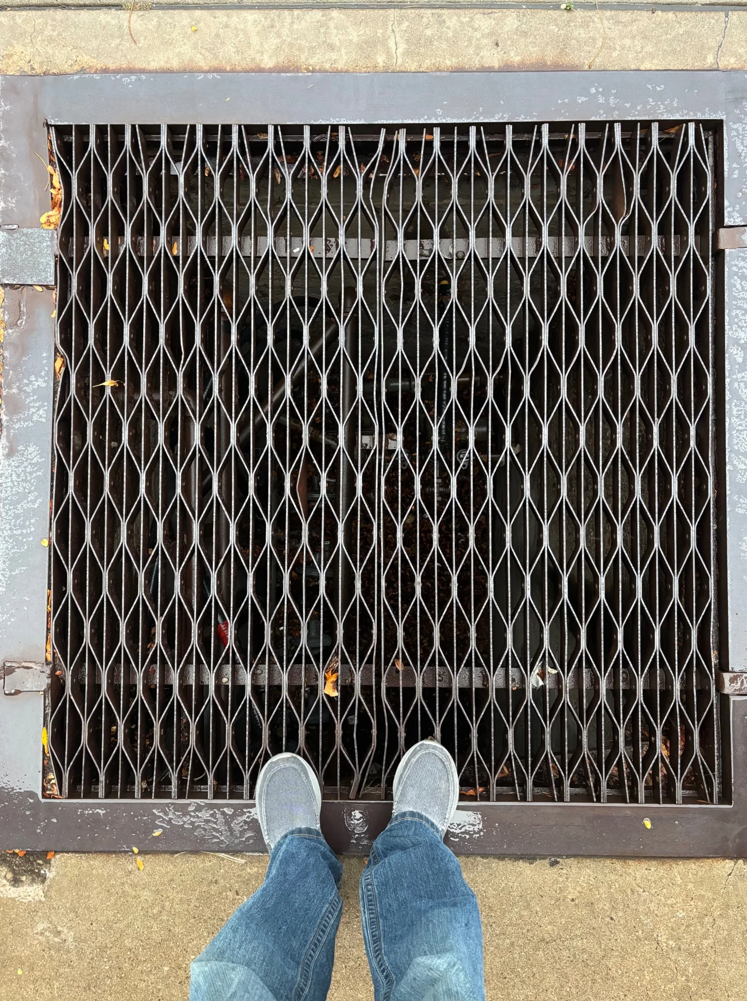 looking down onto a grate of some description, it looks almost endless... the bottom half of my pant-legs and shoes are visible at the bottom of the frame