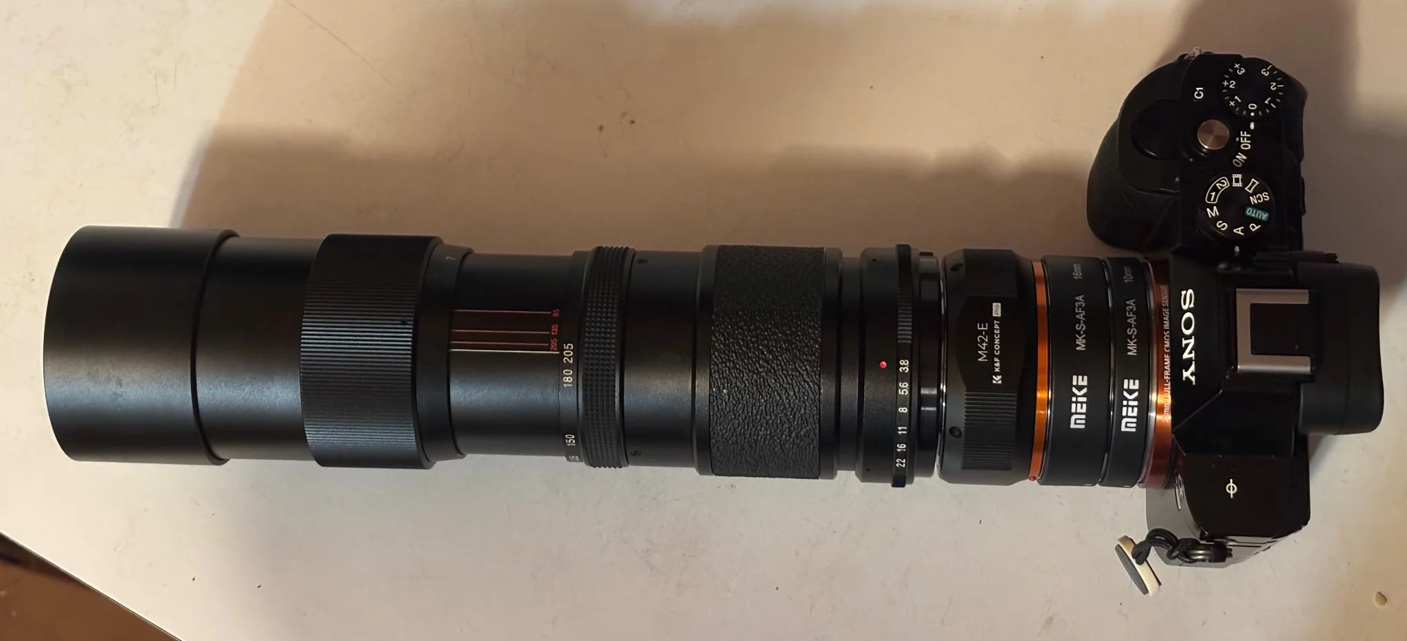 an over 30cm camera stack up consisting of a 85-205mm zoom lens, m42-e mount adapter, a 16mm and 10mm extension tube and a sony a7r